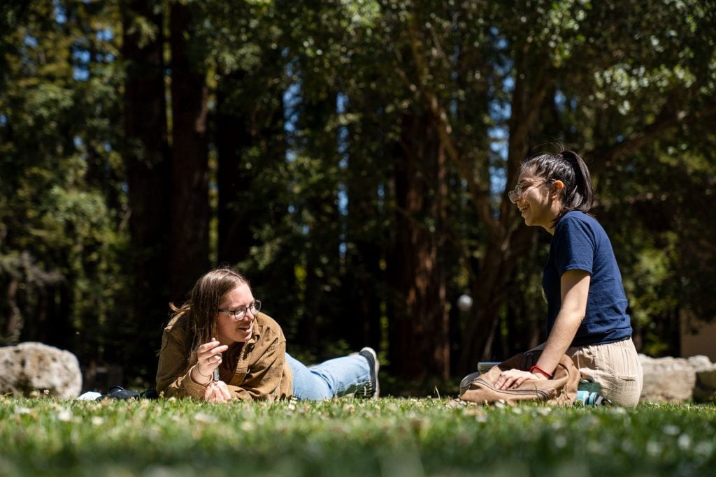 two student laying in the grass